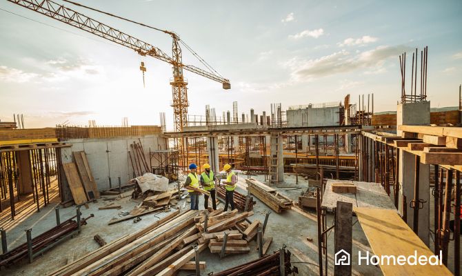 Imprese edili al lavoro in un cantiere: operai con caschi di sicurezza e gru per la costruzione di una struttura in cemento armato - Homedeal