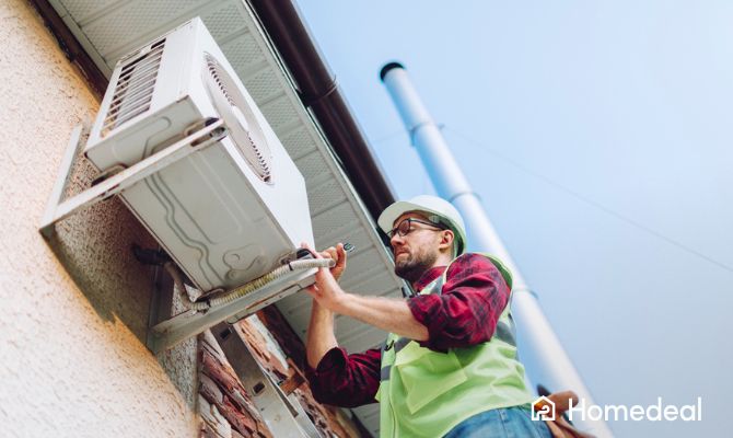 Tecnico installa unità esterna di un condizionatore a parete durante i lavori di montaggio: costo installazione condizionatore - Homedeal