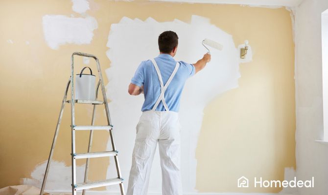 Imbianchino che dipinge una parete con un rullo, utilizzando una scala e attrezzatura professionale per la tinteggiatura - Homedeal