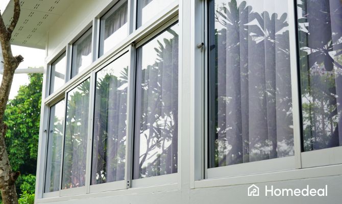 Finestre scorrevoli moderne in alluminio installate su una facciata esterna, con ampie vetrate che aumentano luminosità e visibilità verso il giardino - Homedeal