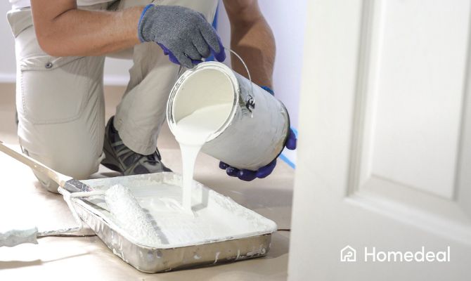 Imbianchino professionista versa pittura bianca per lavori di tinteggiatura interna