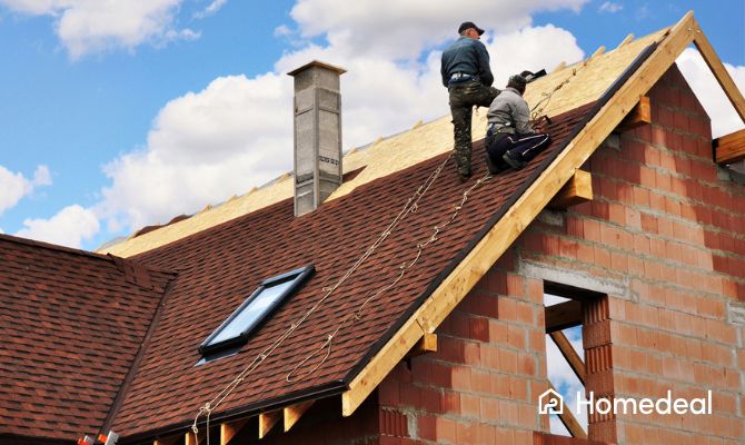 Lavori in corso su un tetto inclinato: operai impegnati nel rifacimento completo della copertura. Focus su quanto costa rifare un tetto a tegole - Homedeal