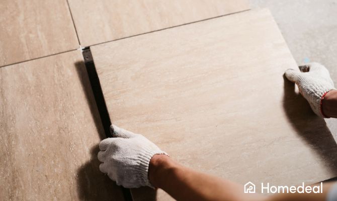Piastrellista professionista posa piastrella grande su pavimento con precisione, indossando guanti da lavoro – Homedeal