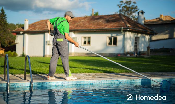 Manutentore piscina che effettua la manutenzione piscina con retino, pulendo l’acqua in un giardino privato - Homedeal