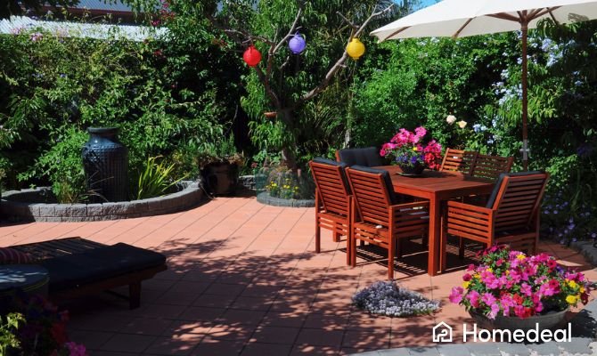 Giardino moderno con pavimento in piastrelle per esterni in cotto, arredato con tavolo in legno, sedie e ombrellone da esterno - Homedeal
